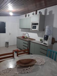 a small kitchen with a table and a microwave at Pé na areia, casa na praia de frente para o mar in Florianópolis