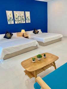 two beds in a room with two tables and a blue wall at Charming and Spacious Beach Homestay 4 Rooms 1 Pool Entire Palace in Hà Bàng