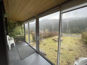 eine abgeschirmte Veranda eines Hauses mit Blick auf ein Feld in der Unterkunft Grand chalet mitoyen dans secteur calme et ensoleillé - FR-1-787-38 in Laveissière + 2 Fotos