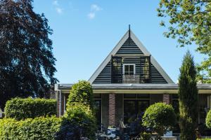 a house with a gambrel roof and bushes at Agapanthus bed and breakfast in Hoogkarspel