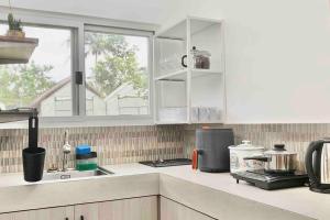 a kitchen with white cabinets and a window at Romantic Cabin Retreat with Garden View and Free Parking in Amadeo