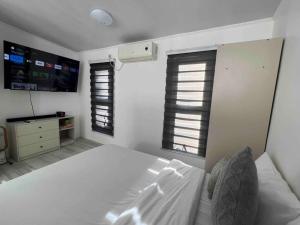 a white bedroom with a bed and two windows at Romantic Cabin Retreat with Garden View and Free Parking in Amadeo