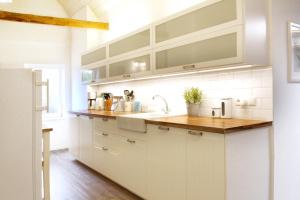 eine Küche mit weißen Schränken und einer hölzernen Arbeitsplatte in der Unterkunft Välkommen in Stralsund