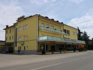 a large yellow building on the side of a street at Hotel San Pellegrino in Spilamberto