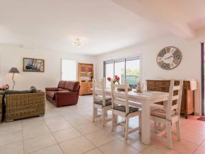 a living room with a table and chairs and a clock at Maison neuve au calme avec jardin clos, proche plage, port et équipements familiaux - FR-1-306-1274 in La Turballe