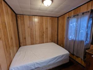 un piccolo letto in una camera in legno con finestra di Tiny Wood Cottage 12 a Wasaga Beach
