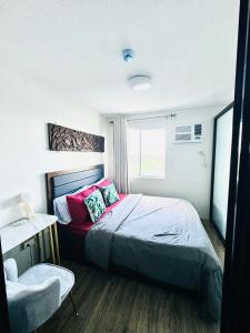 a bedroom with a bed with pink pillows and a window at 2 Bedroom Condo Iloilo City in Iloilo City