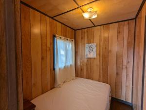 un piccolo letto in una camera in legno con finestra di Tiny Wood Cottage 16 a Wasaga Beach