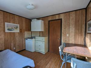 a room with a table and a kitchen with wooden walls at Tiny Wood Cottage 17 in Wasaga Beach
