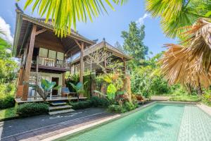 a villa with a swimming pool in front of a house at Ubud Sawah Scenery Villa and Homestay in Tegalalang