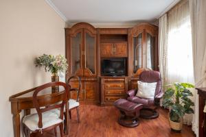 een woonkamer met een tv, een bureau en stoelen bij Apartamento en el centro in Santander