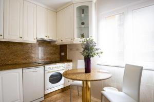 een keuken met witte kasten en een tafel met een vaas met bloemen bij Apartamento en el centro in Santander