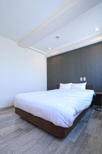 a bedroom with a large bed with white sheets at RE Hotel 谷町9丁目 in Osaka