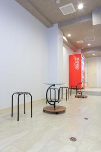 a room with three tables and a red wall at RE Hotel 谷町9丁目 in Osaka