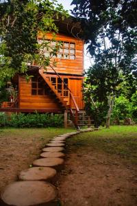 a wooden house with a staircase next to a path at CHOMI HOUSE TAMBOPATA in Puerto Maldonado