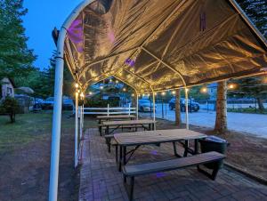 un gruppo di tavoli da picnic sotto una tenda di Tiny Wood Cottage 22 a Wasaga Beach