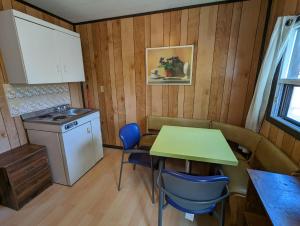 una piccola cucina con tavolo, sedie e piano cottura di Tiny Wood Cottage 22 a Wasaga Beach