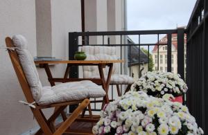 einen Balkon mit 2 Stühlen, einem Tisch und Blumen in der Unterkunft Leon Suite Apartments in Leipzig
