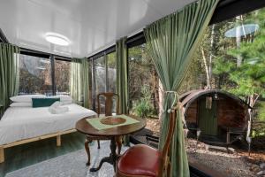 a bedroom with a bed and a table and some windows at Alpine Creek House and Cabin in Merrijig