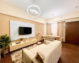 a living room with a couch and a flat screen tv at Baguio Bliss Suites in Baguio