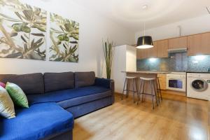 a living room with a blue couch and a kitchen at PORTAL DEL ANGEL Barcelonastuff Apartments in Barcelona