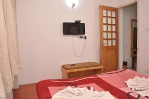 a bedroom with a bed and a tv on the wall at Lilly's Valley Resort in Kodaikānāl