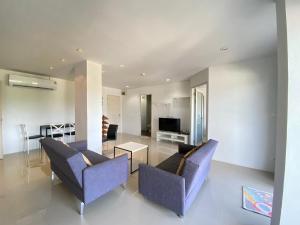 a living room with two blue chairs and a television at Mosaic Condo B44-45M in Ban Tha Fat