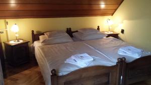 ein Schlafzimmer mit einem Bett mit weißer Bettwäsche und zwei Lampen in der Unterkunft Kocsis Panzió és Étterem in Komárom