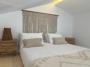 a bedroom with a large bed with white sheets and pillows at Casa Ingrina in Carrapateira