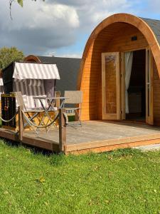 a deck with a chair and a table in front of a house at 11 Premium Camping Pod "Nordstrand" in Silberstedt
