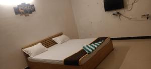 a bed in a room with a tv on the wall at Spacious AC rooms with Swimming Pool Access in Covelong