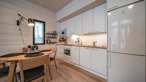 a kitchen with a table and a refrigerator at Pitkäkuusen mökki in Äkäslompolo +26 photos