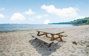 a picnic table sitting on a beach next to the water at Golfparken in Løjt +2 photos