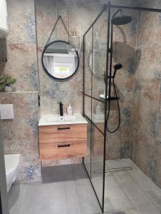 a bathroom with a shower with a sink and a mirror at Apartament nad Jeziorem Drwęckim w Ostródzie z klimatyzacją in Ostróda