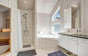 a bathroom with a tub and a shower and a sink at Holiday Home Mælkebøttevej Væggerløse Ii in Marielyst +19 photos