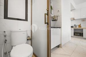 a white bathroom with a toilet and a mirror at Belia by Kozystay - BSD in Tangerang +16 photos