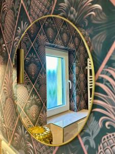 ein Spiegel in einem Badezimmer mit einem Fenster an einer Wand in der Unterkunft Villa Pauline - FeWo Bretagne in Bad Sooden-Allendorf