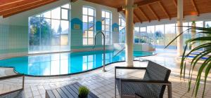 a large swimming pool in a building with glass windows at Alte Dorfschule im Recknitztal in Selpin