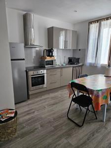 una cucina con tavolo e una cucina con piano cottura e frigorifero. di Chez Marie appartement centre historique Perpignan a Perpignano
