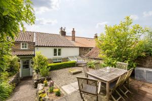 a garden with a table and chairs in front of a house at Robins Cottage - Beautiful North Yorkshire Stone Cottage in York