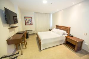 a bedroom with a bed and a desk and a television at Hotel Marcelius in Guayaquil