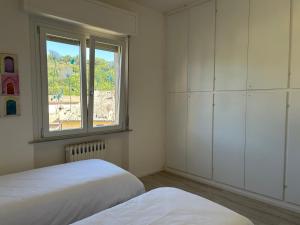 a white bedroom with two beds and a window at Appartamento Moderno al Centro di Spoleto in Spoleto