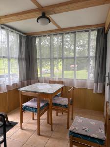 a dining room with a table and chairs and windows at Retro chatky Hůrka Lipno in Horní Planá