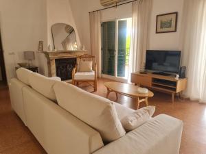 a living room with a white couch and a television at Casa dos Arcos in Olhos de Água
