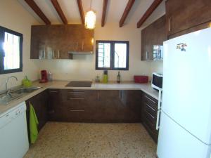 een keuken met bruine kasten en een witte koelkast bij CASA CHOULOU Moraira in Moraira