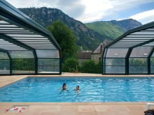 two people in a swimming pool with mountains in the background at ArriuMage in Bielle