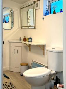 La salle de bains est pourvue de toilettes, d'un lavabo et de miroirs. dans l'établissement Lily s Pad - Private retreat in Lymington, New Forest, à Lymington 53 autres photos