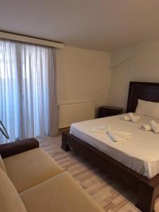 a bedroom with a bed and a couch and a window at revisapartments brown in Neos Marmaras