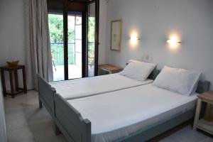 a bedroom with a bed with white sheets and a window at Mirsini Apartments in Kariotes