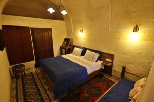 a bedroom with a bed with a blue comforter at Demisos Caves Hotel in Urgup
